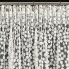 Biała firana gotowa EUROFIRANY Daisy o wymiarach 130 x 270 cm, ozdobiona jest delikatnym wzorem kwiatowym i zawieszona na metalowym karniszu za pomocą klipsów.