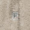 Beżowy koc o puszystej fakturze z widoczną metką, na której znajduje się napis: "design 91 for your home".