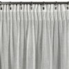 Biała zasłona o wymiarach 140 x 270 cm z delikatnym, ażurowym wzorem, zawieszona na metalowym karniszu za pomocą klipsów. Produkt to "Zasłona EUROFIRANY Aleksa".