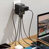 Czarny adapter podróżny DUDAO A35PRO 35W jest podłączony do gniazdka ściennego, z kilkoma kablami ładującymi różne urządzenia elektroniczne na biurku. Na adapterze widoczne jest logo "DUDAO".