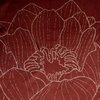 Ceglasty bieżnik z delikatnym, błyszczącym wzorem przedstawiającym kwiaty. Materiał ma gładką teksturę i subtelny połysk, co nadaje mu elegancki wygląd.