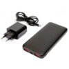 Na zdjęciu znajduje się czarny powerbank z dwoma czerwonymi portami USB oraz ładowarka z wtyczką i kablem USB. Na ładowarce widoczne są oznaczenia techniczne i certyfikaty.