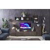 W elegancko urządzonym salonie na ścianie wisi telewizor z widocznym ekranem, na którym wyświetlają się napisy: "HYUNDAI", "32''", "android tv", "DOLBY DIGITAL PLUS". Wokół telewizora znajdują się drewniane meble, dekoracje oraz rośliny, tworząc nowoczesn