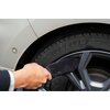 Na zdjęciu widoczna jest ręka trzymająca czarną rękawicę do mycia, która dotyka felgi samochodowej. Na oponie widoczny jest napis "MICHELIN PRIMACY".