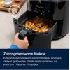 Na zdjęciu widoczna jest frytkownica beztłuszczowa z wysuniętą szufladą pełną frytek, a na wyświetlaczu urządzenia widnieje napis "185°C 04'". Na dole zdjęcia znajduje się tekst: "Zaprogramowane funkcje. Funkcja przypomnienia o potrząśnięciu potrawą ułatw