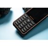 Telefon komórkowy z widoczną klawiaturą numeryczną, przyciskiem "OK" oraz logo "ulefone" na obudowie. Urządzenie ma czarną obudowę z pomarańczowymi akcentami, leży na jasnoniebieskim tle.
