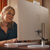 Na zdjęciu znajduje się komputer typu All-in-One marki HP, ustawiony na drewnianym biurku. Obok komputera widoczna jest klawiatura i myszka, a w tle znajduje się obrazek z kangurem oraz fragment instrumentu muzycznego.