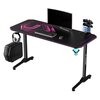 Czarne biurko gamingowe z różowymi akcentami świetlnymi, na którym znajdują się monitor, klawiatura, myszka oraz stojak na kontrolery. Na blacie widoczny jest napis "ULTRADESK", a na nogach biurka logo producenta.