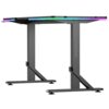 Czarne biurko gamingowe z podświetleniem RGB na krawędziach blatu, z solidnymi metalowymi nogami w kształcie litery T. Na jednej z nóg widoczne jest logo i napis "ULTRADESK".