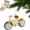 Ozdoba choinkowa w kształcie roweru w kolorach żółtym, brązowym i srebrnym, zawieszona na gałązce choinki. Widoczne jest logo z napisem "CHRISTMAS JOYFUL TIME DECORATION" oraz złoty sznurek do zawieszenia.