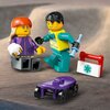 Na niebieskim tle widoczne są dwie figurki LEGO, jedna z nich trzyma białą torbę z zielonym symbolem medycznym. Obok nich znajduje się fioletowa deskorolka na rampie z czarną poręczą i czerwoną podstawą.