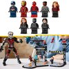 Na zdjęciu widoczne są figurki LEGO przedstawiające postacie w kolorowych strojach, w tym niebieskim, czerwonym i czarnym, ustawione w dwóch rzędach. Poniżej znajduje się scena z klocków LEGO przedstawiająca bitwę, z dużą figurką robota oraz mniejszymi po