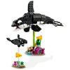 Na zdjęciu znajduje się zestaw klocków LEGO przedstawiający dwie orki na podstawach z elementami przypominającymi rośliny morskie. Większa orka jest uniesiona na zielonym wsporniku, a mniejsza na przezroczystym, obie otoczone są kolorowymi klockami imituj