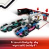 Na zdjęciu znajduje się zestaw klocków przedstawiający garaż F1 z dwoma bolidami, w tle widoczne są elementy garażu z ekranami i trofeum. Na dole zdjęcia znajduje się tekst: "Przesuń dźwignię, aby wystrzelić bolidy F1".