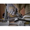 Ręka w rękawicy z logo "STANLEY" trzyma wąż, który jest podłączany do pilarki ukosowej. Na urządzeniu widoczny jest napis: "STANLEY PROPERLY SECURE BRACKET WITH BOTH SCREWS BEFORE USE."