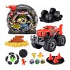 Na zdjęciu znajduje się zestaw kreatywny ZURU Monster Truck Smashers 74105EMSLB, w skład którego wchodzi czerwony monster truck, różne akcesoria, figurki oraz elementy do budowy. Opakowanie ma grafikę czaszki z napisem "Smashers Monster Trucks" i informac