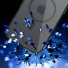 Przezroczysto-zielone etui na telefon z widocznym logo w kształcie jabłka jest przedstawione na tle niebieskich, rozpryskujących się elementów. W centralnej części etui znajduje się okrągły wzór, który sugeruje kompatybilność z technologią MagSafe.