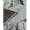 Zdjęcie przedstawia fragment szarego dywanu zewnętrznego o nazwie "MULTI-DECOR Dara" o wymiarach 120 x 170 cm, z widocznym detalem wzoru i krawędzią z brązowym obszyciem. Dywan ma zróżnicowaną teksturę i kolorystykę, łączącą odcienie szarości i czerni.