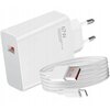 Biała ładowarka sieciowa z dwoma bolcami oraz złączem USB, obok której znajduje się zwinięty biały kabel USB z pomarańczowymi elementami. Na ładowarce widoczny jest napis "67W" oraz "Xiaomi Communications Co., Ltd."