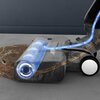 Obraz przedstawia elektryczny mop z przezroczystą obudową, ukazującą wewnętrzny mechanizm z niebieskim światłem i strzałkami wskazującymi kierunek przepływu. Na podłodze widoczna jest rozlana ciecz, którą mop skutecznie zbiera, co ilustruje jego funkcję c