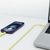 Na zdjęciu widać żółty kabel USB Typ-C - Lightning podłączony do fioletowego smartfona i laptopa. Na ekranie smartfona wyświetla się ikona ładowania oraz napis "100%".
