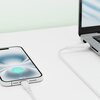 Na zdjęciu widać biały kabel USB-C podłączony do smartfona i laptopa, leżący na białej powierzchni. Na ekranie smartfona widoczny jest symbol ładowania oraz napis "98%".