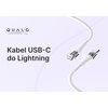 Na zdjęciu widoczny jest biały kabel USB-C do Lightning z przezroczystymi elementami, a w tle znajduje się napis "QUALO TRANSPARENT LINE" oraz "Kabel USB-C do Lightning". Kabel ma plecioną strukturę i jest przedstawiony na jasnym tle.