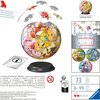 Na zdjęciu znajduje się kula z puzzli 3D z motywem Pokémon, składająca się z 73 elementów, o średnicy 12,9 cm, umieszczona na czarnej podstawce. Widoczne są również instrukcje montażu, ostrzeżenia w różnych językach oraz logo "Ravensburger" w prawym dolny