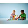Na zdjęciu widoczny jest zestaw klocków LEGO 10453 DUPLO Peppa Pig Wesołe miasteczko, w tym diabelski młyn z kolorowymi gondolami oraz inne elementy placu zabaw. Na górze zdjęcia znajduje się tekst: "Figurki kręcą się w gondolach diabelskiego młyna!".