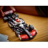 Na zdjęciu znajduje się model bolidu F1 z klocków LEGO, umieszczony na drewnianej powierzchni. Na przedniej części bolidu widoczne są napisy "Money" i "Gram", a na środku logo "Haas".