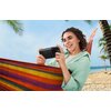 Osoba leży na kolorowym hamaku na plaży, trzymając w rękach smartfon z podłączonym powerbankiem ECOFLOW Rapid Magnetic 10000 mAh 65W Czarny. W tle widać palmy i morze pod jasnym, niebieskim niebem.