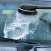 Na zdjęciu widać czarną szczotkę rotacyjną, która myje tylną szybę i karoserię niebieskiego samochodu, z widocznymi kroplami wody. Na karoserii znajduje się emblemat z napisem "TDI", a obok widoczna jest część tablicy rejestracyjnej z literami "BG".