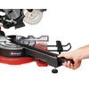Na zdjęciu znajduje się pilarka ukosowa z widocznym ostrzem i mechanizmem regulacji kąta cięcia. Na podstawie urządzenia widnieje logo "Einhell", a ręka trzyma uchwyt do regulacji.