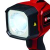 Czerwona lampa warsztatowa z czarnymi elementami, posiadająca kwadratowy reflektor z przezroczystą osłoną. Na obudowie widoczne jest logo "Einhell" oraz żółty znak ostrzegawczy.