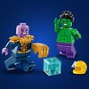 Na zdjęciu znajdują się dwie figurki LEGO przedstawiające postacie w dynamicznych pozach, jedna z fioletową głową i złotą zbroją, druga zielona z czarnymi włosami. Obok figurek widoczne są przezroczysty niebieski sześcian i żółty hełm.