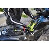 Na zdjęciu widać motocykl z otwartym schowkiem, w którym znajduje się urządzenie rozruchowe marki RYOBI, podłączone do akumulatora za pomocą czerwonych przewodów. Na urządzeniu widoczny jest napis "RYOBI" oraz kilka przycisków i wyświetlacz.