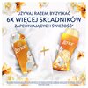 Na zdjęciu znajdują się dwa produkty marki Lenor, otoczone białymi i pomarańczowymi kwiatami, z napisem: "Używaj razem, by zyskać 6x więcej składników zapewniających świeżość*". Na dole widoczna jest informacja: "*Składniki zapewniające świeżość zawarte w
