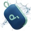 Niebieski głośnik mobilny z zielonymi akcentami i dużym logo "q" na siatce, otoczony rozpryskującą się wodą. Na bocznej krawędzi widoczne są przyciski sterujące oraz napis "Select 4 Go".