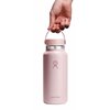 Różowa butelka termiczna z logo Hydro Flask na przodzie, posiada szeroki ustnik z elastycznym uchwytem. Na butelce widoczny jest napis "Hydro Flask".