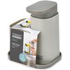 Szary dozownik do płynu do naczyń z uchwytem na gąbkę marki Joseph Joseph Duo, zaprezentowany w opakowaniu z napisem "Soap Pump with sponge holder" oraz "Tidy sink storage". Na opakowaniu widoczna jest ilustracja przedstawiająca produkt w użyciu.