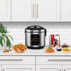 Na zdjęciu znajduje się multicooker TurboTronic TT-DMC21 z wyświetlaczem cyfrowym, ustawiony na blacie kuchennym, otoczony różnorodnymi potrawami oraz broszurą reklamową. W tle widoczne są białe szafki kuchenne i roślina doniczkowa.