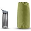 Na zdjęciu znajduje się przezroczysta butelka z szarym ustnikiem i napisem "CAMELBAK eddy" oraz zielona mata samopompująca w pokrowcu z delikatnym wzorem geometrycznym.