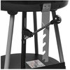 Czarno-srebrny grill węglowy z widocznym mechanizmem regulacji wysokości rusztu, oparty na trzech metalowych nogach. Na dolnej półce znajduje się naklejka z piktogramami i ostrzeżeniami.
