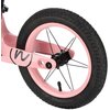 Różowe koło rowerka biegowego z czarną oponą i metalowymi szprychami, na ramie widoczne jest czarne logo w kształcie litery "W". Na oponie znajduje się napis: "INFLATE 10-20 PSI (0.7-1.3 BAR) 57-203 (12 1/2 x 2 1/4)".