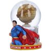 Na zdjęciu znajduje się kula śnieżna z figurką superbohatera w niebieskim stroju z czerwonym płaszczem, obok której widoczny jest model budynku z napisem "DAILY PLANET" na złotej kuli. Podstawa kuli ozdobiona jest napisem "SUPERMAN" oraz białymi gwiazdami