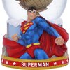 Figurka przedstawia postać w niebieskim stroju z czerwonym płaszczem, stojącą przed kulą śnieżną z modelem globu. Na podstawie znajduje się napis "SUPERMAN" otoczony białymi gwiazdami na czerwonym tle.