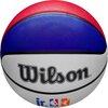 Na zdjęciu znajduje się piłka do koszykówki w kolorach czerwonym, niebieskim i białym, z widocznym logo "Wilson" oraz symbolami "jr. NBA".