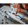 Na zdjęciu widoczny jest model LEGO myśliwca z rozłożonymi skrzydłami, z dwoma strzałkami wskazującymi kierunek ich ruchu. Na dole znajduje się napis: "Ustaw skrzydła w kultowej formacji 'V'".