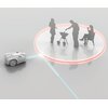 Na zdjęciu znajduje się robot koszący oraz sylwetki trzech osób, z których jedna siedzi, a dwie stoją przy grillu. Robot koszący jest oddzielony od osób okręgiem z czerwonym obramowaniem, a od niego biegnie niebieska linia w kierunku robota.