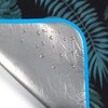 Zdjęcie przedstawia fragment koca piknikowego z motywem liści, z widoczną niebieską lamówką. Na srebrnej, wodoodpornej powierzchni koca znajdują się krople wody.